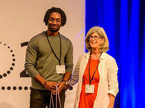Emmanuel Aneke (APS), winner of SRI 2024 Science Communication Poster Prize ('Public voting'), together with the lightsources.org representative Silvana Westbury (right). (Photo: DESY)